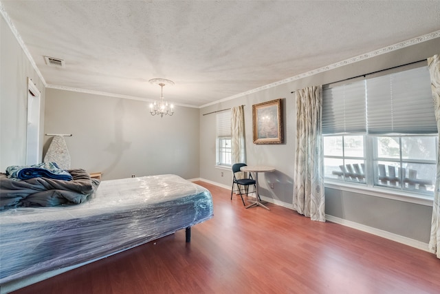 bedroom with a textured ceiling, hardwood / wood-style flooring, crown molding, and a notable chandelier