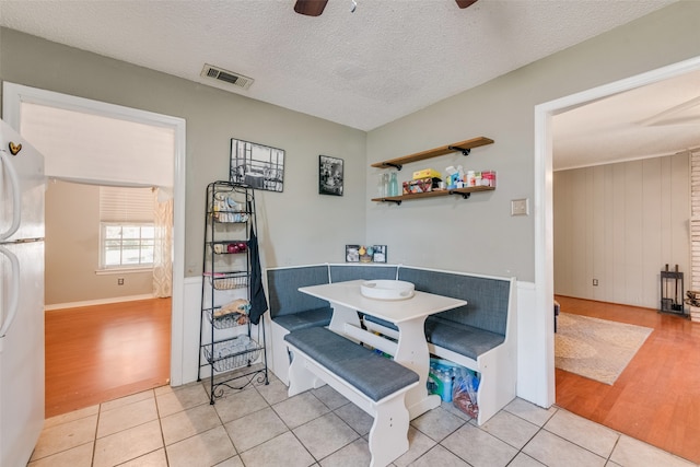 dining area featuring light hardwood / wood-style flooring, a textured ceiling, and ceiling fan