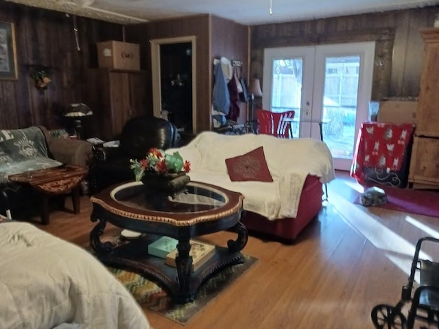 living room with wooden walls, french doors, and hardwood / wood-style flooring