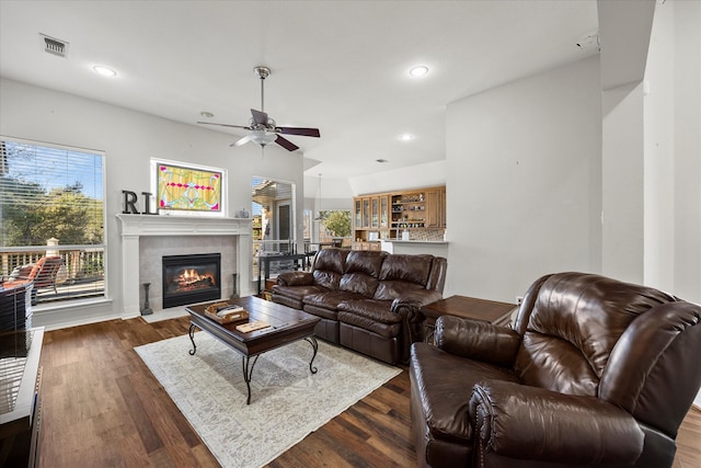 living room with ceiling fan, dark wood-type flooring, and a tiled fireplace