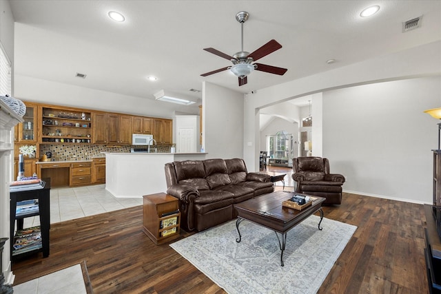 living room with ceiling fan, vaulted ceiling, and light hardwood / wood-style flooring