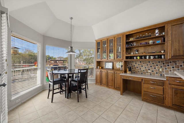 dining space featuring light tile patterned flooring, built in desk, and vaulted ceiling