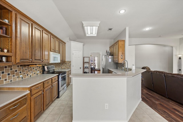 kitchen featuring sink, tasteful backsplash, light tile patterned floors, appliances with stainless steel finishes, and kitchen peninsula