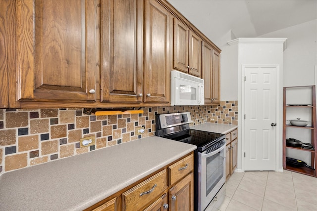 kitchen with lofted ceiling, electric stove, light tile patterned floors, and tasteful backsplash