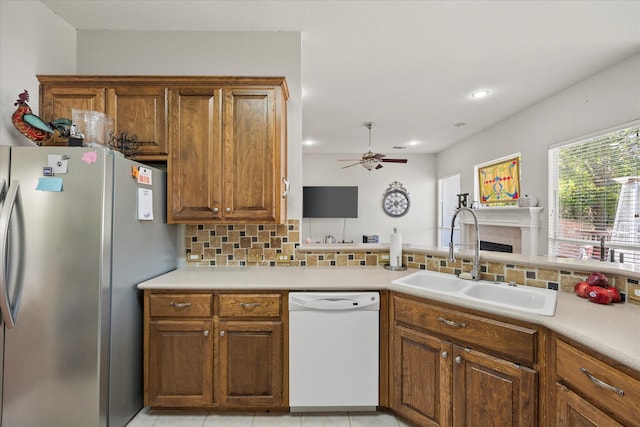 kitchen with decorative backsplash, sink, light tile patterned floors, dishwasher, and stainless steel refrigerator