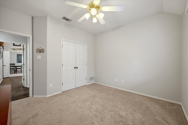 unfurnished bedroom featuring lofted ceiling, a closet, ceiling fan, and carpet