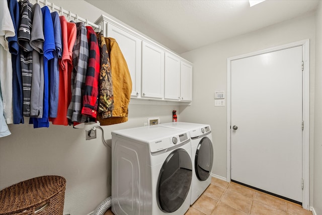 washroom featuring cabinets, washing machine and dryer, and light tile patterned floors