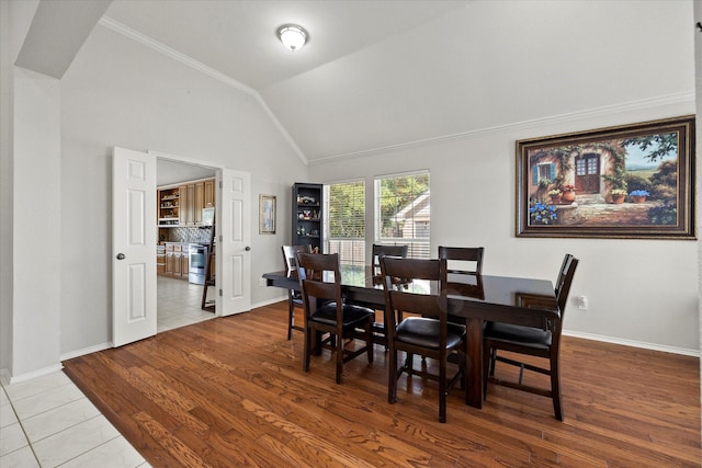 tiled dining area with lofted ceiling and ornamental molding