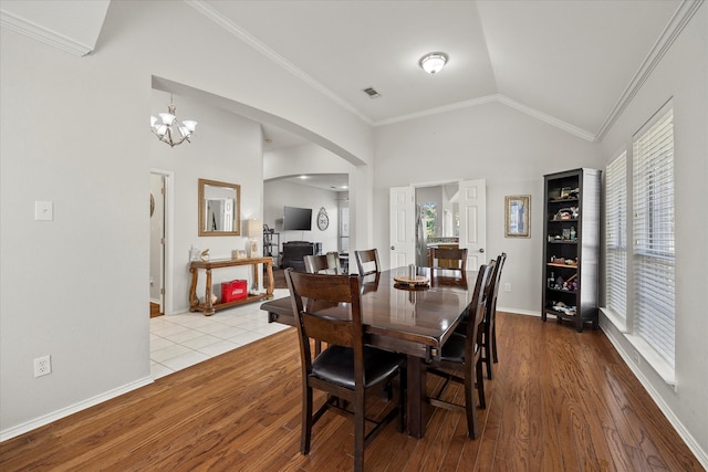 dining area featuring a notable chandelier, light hardwood / wood-style floors, lofted ceiling, and ornamental molding