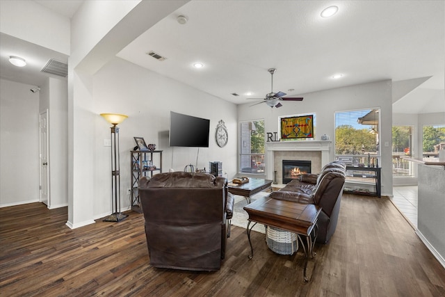 living room featuring ceiling fan, a tile fireplace, dark hardwood / wood-style floors, and a healthy amount of sunlight