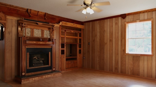 unfurnished living room featuring wood-type flooring, ceiling fan, and wooden walls