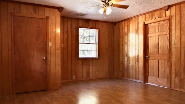 unfurnished bedroom featuring hardwood / wood-style flooring, ceiling fan, and wooden walls