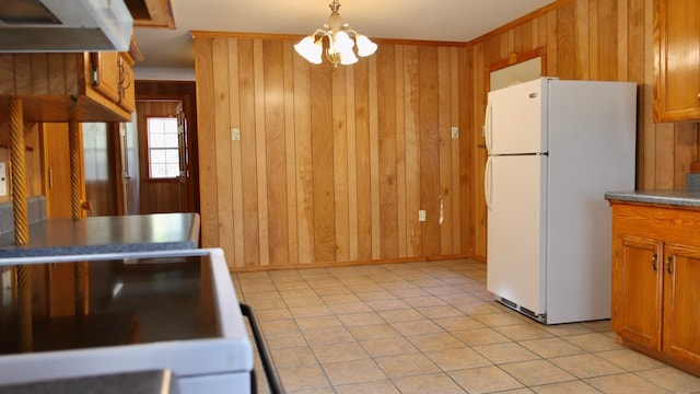 kitchen with light tile patterned floors, an inviting chandelier, white fridge, hanging light fixtures, and wood walls