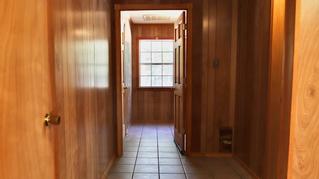 hall featuring tile patterned floors and wood walls