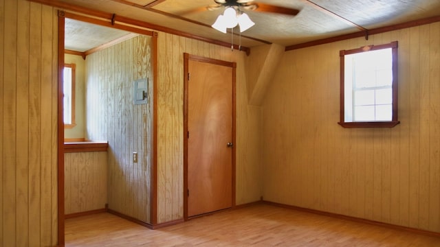 unfurnished bedroom with ceiling fan, wood walls, and light hardwood / wood-style floors