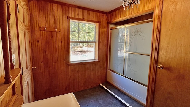 doorway to outside with wood walls, dark tile patterned flooring, and ornamental molding