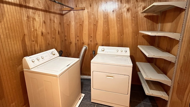 washroom featuring wood walls, washing machine and dryer, and dark tile patterned floors