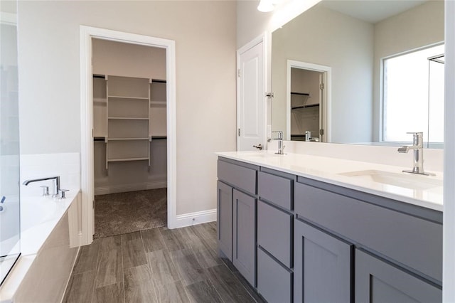 bathroom featuring tiled bath, hardwood / wood-style floors, and vanity