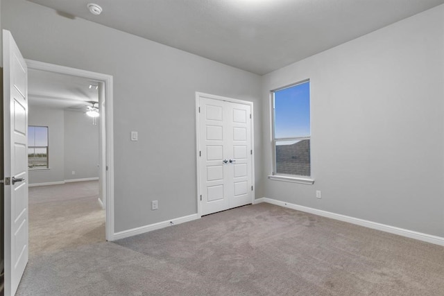 unfurnished bedroom with light colored carpet and multiple windows