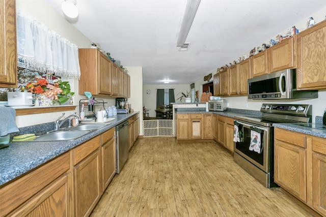 kitchen featuring kitchen peninsula, light wood-type flooring, stainless steel appliances, and sink