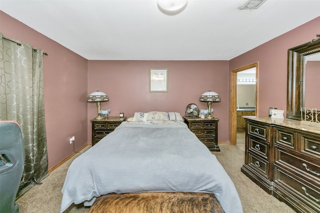 bedroom featuring connected bathroom and light carpet