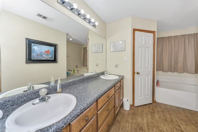 bathroom with hardwood / wood-style flooring, vanity, and a tub