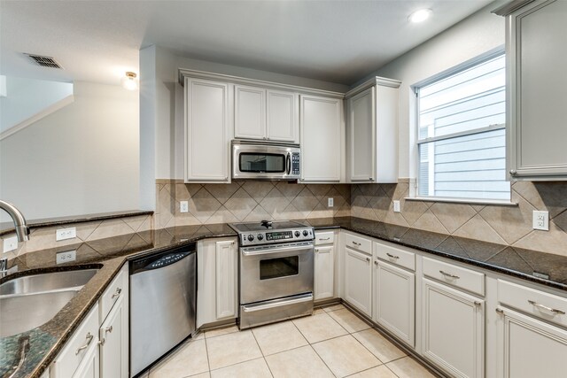 kitchen featuring dark stone counters, decorative backsplash, appliances with stainless steel finishes, and sink