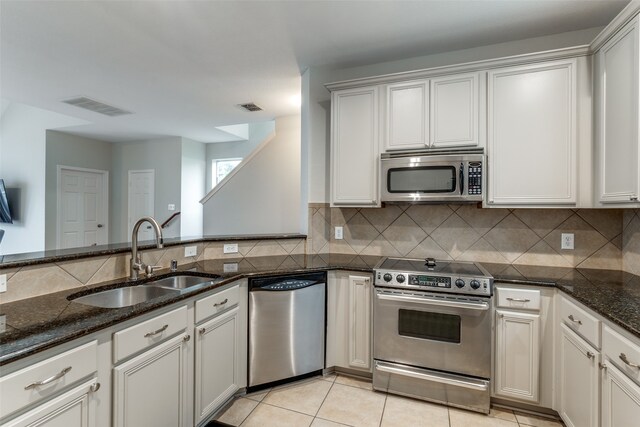 kitchen featuring dark stone counters, white cabinetry, sink, and stainless steel appliances