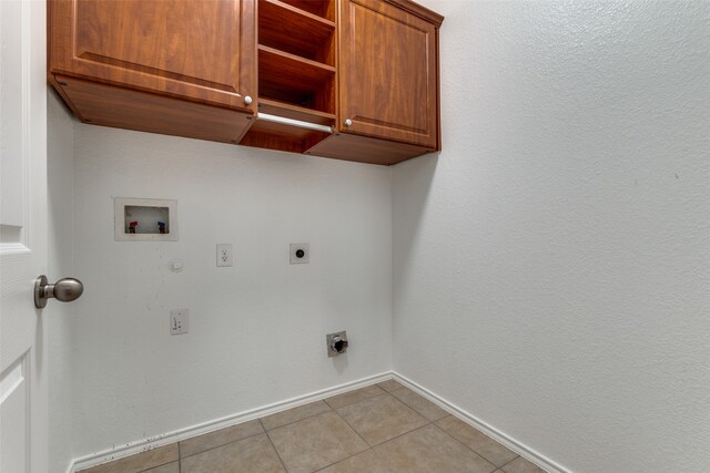 clothes washing area featuring cabinets, electric dryer hookup, hookup for a washing machine, and light tile patterned floors