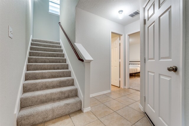 stairway featuring a textured ceiling and tile patterned floors