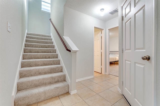 staircase with tile patterned flooring and a textured ceiling