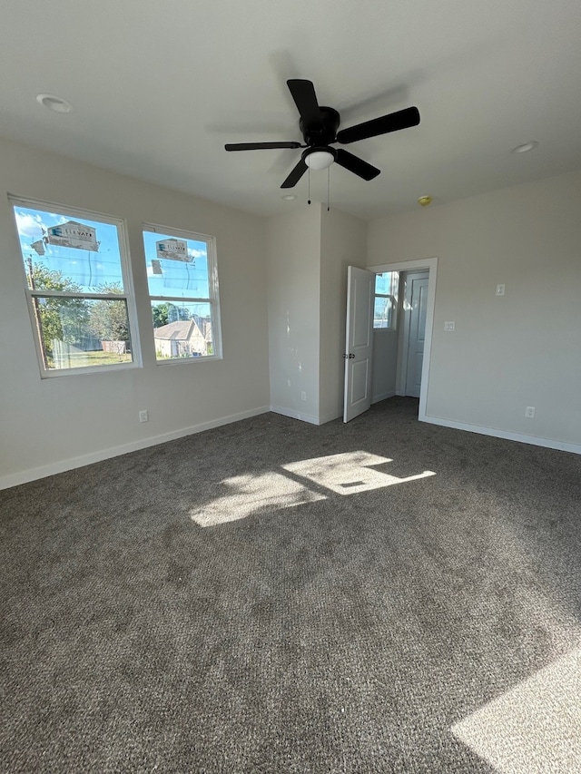 empty room with dark colored carpet and ceiling fan