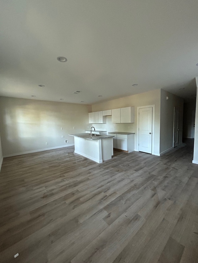 kitchen with light hardwood / wood-style floors, sink, a center island with sink, and white cabinets