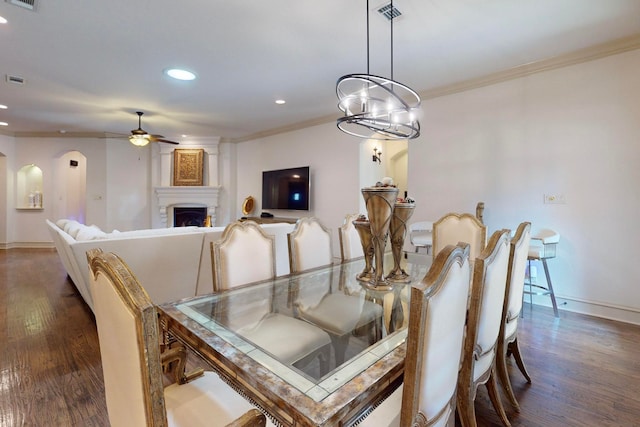 dining area with ornamental molding, a fireplace, ceiling fan with notable chandelier, and dark wood-type flooring