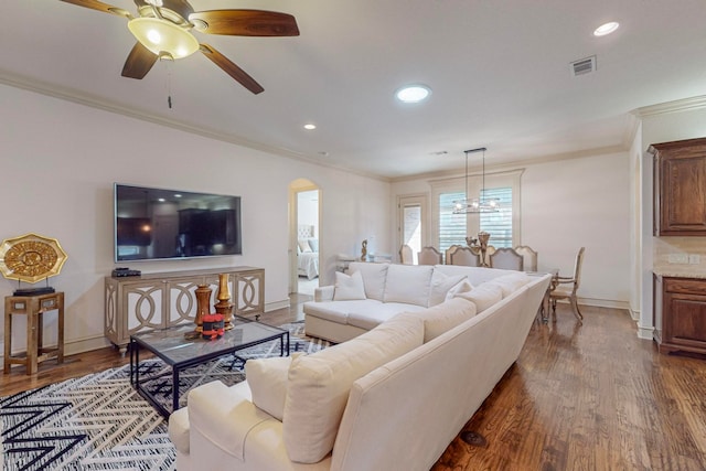 living room with ceiling fan with notable chandelier, dark wood-type flooring, and crown molding