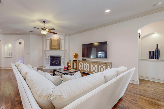 living room with dark hardwood / wood-style flooring, ceiling fan, a large fireplace, and crown molding