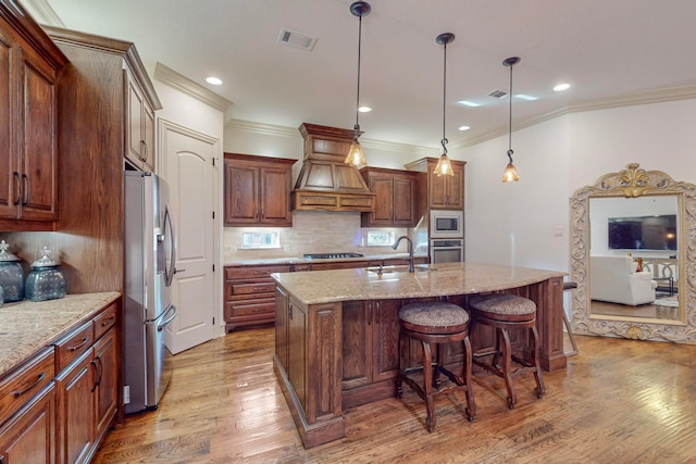 kitchen with a center island with sink, light hardwood / wood-style flooring, sink, custom range hood, and appliances with stainless steel finishes