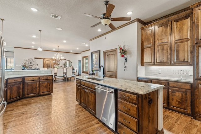 kitchen featuring a center island with sink, light wood-type flooring, decorative light fixtures, sink, and dishwasher