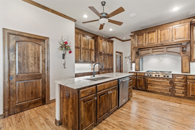 kitchen with sink, appliances with stainless steel finishes, backsplash, an island with sink, and light hardwood / wood-style flooring