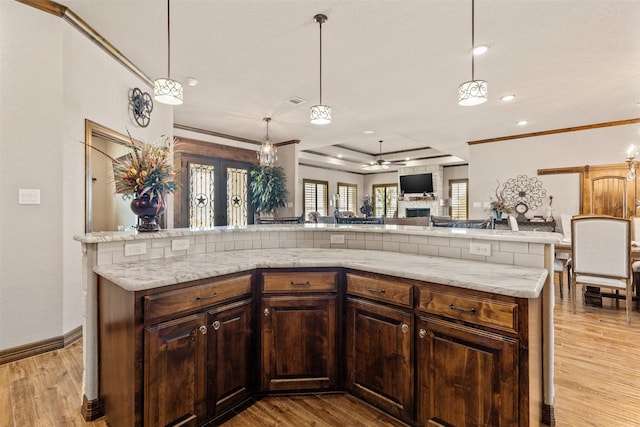 kitchen with a stone fireplace, decorative light fixtures, and light hardwood / wood-style floors