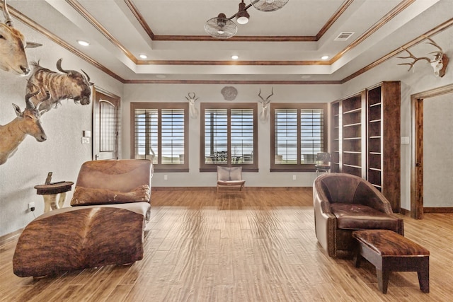 sitting room with a raised ceiling, light hardwood / wood-style floors, and crown molding