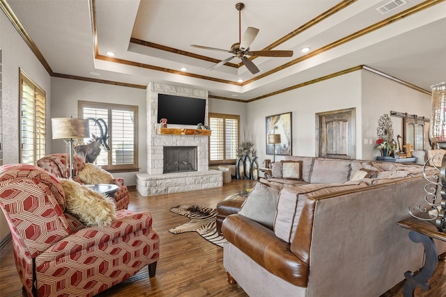 living room with dark wood-type flooring, a raised ceiling, ornamental molding, and a fireplace