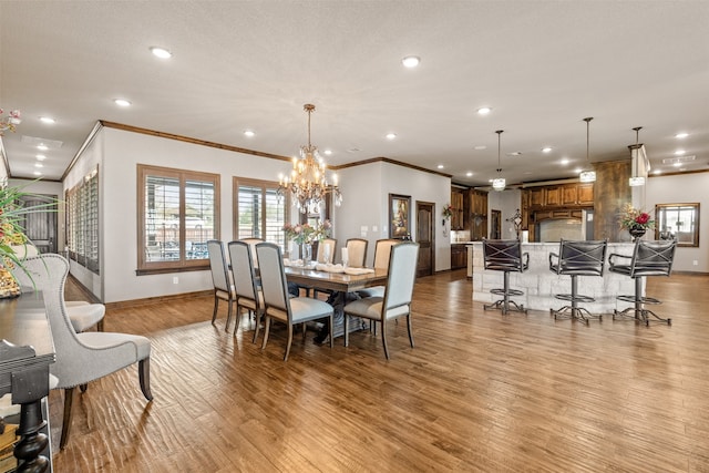 dining space featuring a textured ceiling, light hardwood / wood-style flooring, a chandelier, and crown molding