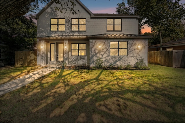 back house at dusk featuring a lawn