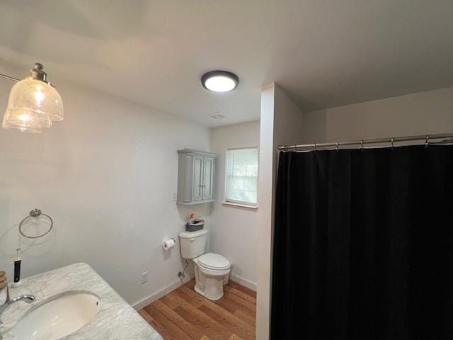 bathroom featuring toilet, hardwood / wood-style flooring, curtained shower, and vanity