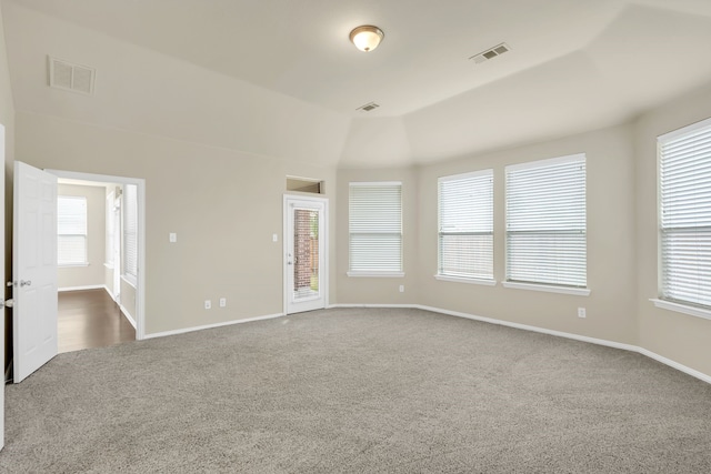 carpeted empty room with vaulted ceiling