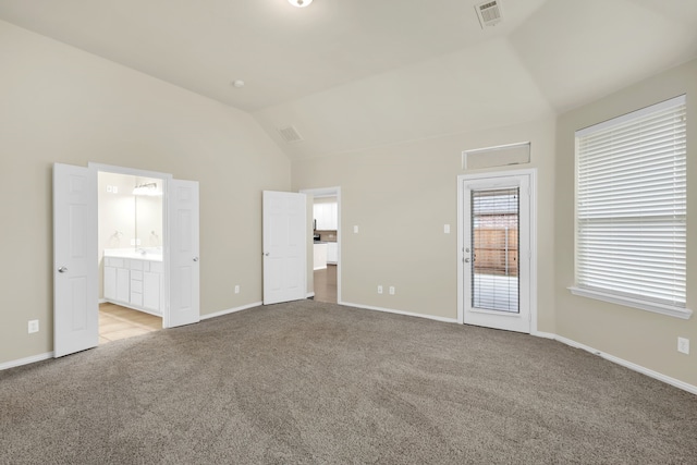 unfurnished bedroom featuring light colored carpet, ensuite bath, and lofted ceiling