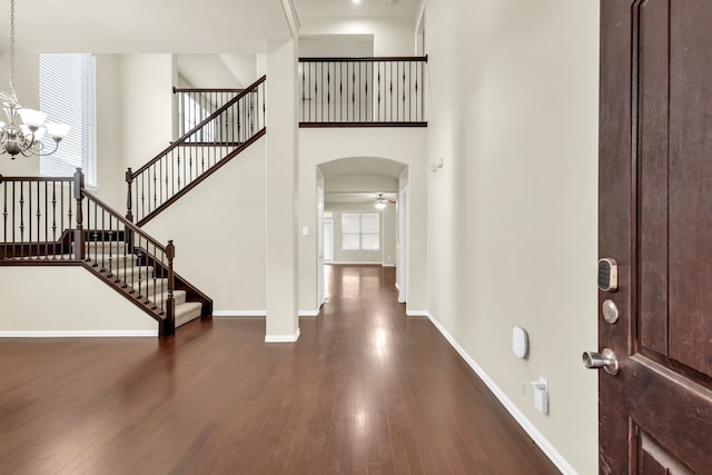 entryway featuring a towering ceiling, dark hardwood / wood-style floors, and ceiling fan with notable chandelier