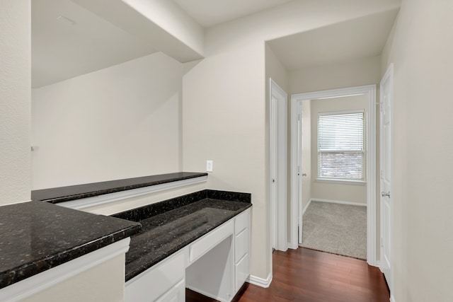 kitchen with dark wood-type flooring, dark stone countertops, and white cabinets