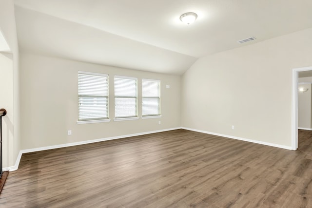 spare room with dark wood-type flooring and lofted ceiling